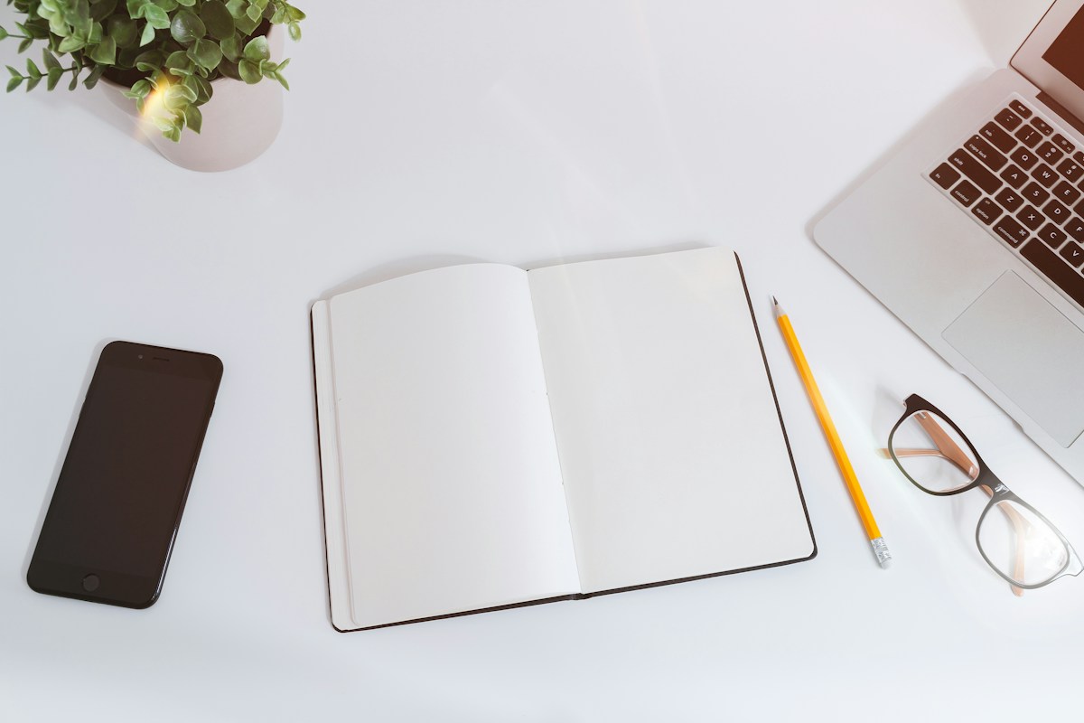 Organised workspace with a notebook, phone and laptop